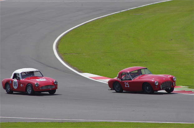 Zwei rote Autos auf einer Rollbahn mit einer Rasenfläche auf der rechten Seite.
