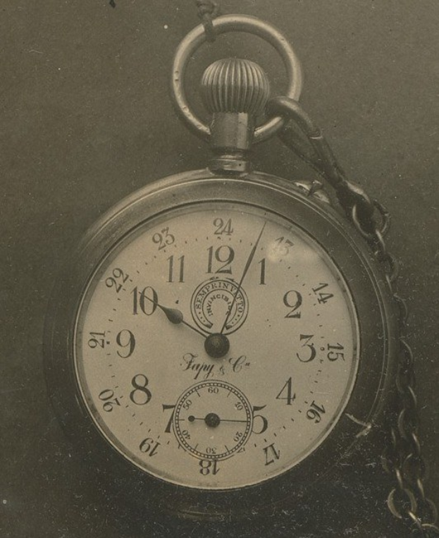 Ein Schwarz-Weiß-Foto einer antiken Taschenuhr mit einer Kette, das eine nummerierte Zifferblatt zeigt.