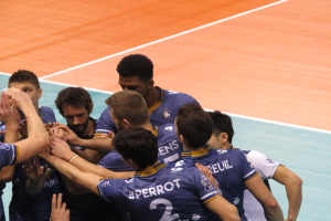 Eine Gruppe von Männern in blauen 'Ligue 1'-T-Shirts feiert auf einem Volleyballfeld.