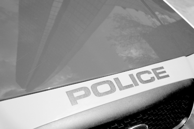 Ein Polizeifahrzeug mit einer Reflexion eines Gebäudes und Baums auf seiner Oberfläche.