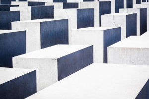 Luftaufnahme des Holocaust-Mahnmals für die ermordeten Juden Europas in Berlin, das zahlreiche weiße und blaue rechteckige Betonsteine in einem Gittermuster zeigt.