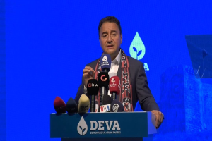 Ein Mann in Mantel und Schal steht hinter einem Pult mit Mikrofonen und liest eine Tafel, auf der steht "deva ceo sagt, dass es keine gute Idee für die Zukunft ist."