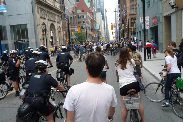 Gebäude säumen eine Straße, auf der ein paar Menschen Fahrräder fahren.