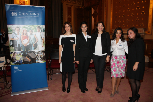 Eine Fahne links, Stühle im Hintergrund, fünf Frauen rechts und eine Wand im Hintergrund.