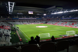 Großes Stadion voller Zuschauer bei einem Fußballspiel im Estadio Santiago Bernabeu, Madrid, Spanien, mit sitzenden und stehenden Zuschauern unter Stadionbeleuchtung und einem großen Bildschirm.