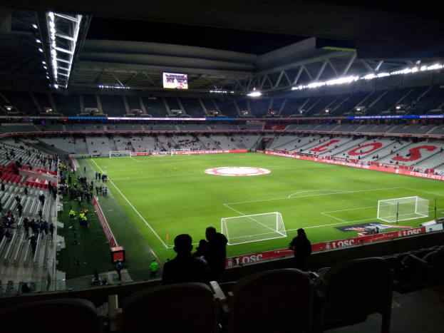 Großes Stadion voller Zuschauer bei einem Fußballspiel im Estadio Santiago Bernabeu, Madrid, Spanien, mit sitzenden und stehenden Zuschauern unter Stadionbeleuchtung und einem großen Bildschirm.