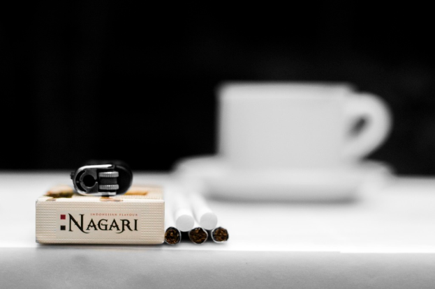 Eine Tasse und ein Unterteller, Zigaretten, Müll und eine Schachtel sind auf einem Tisch.