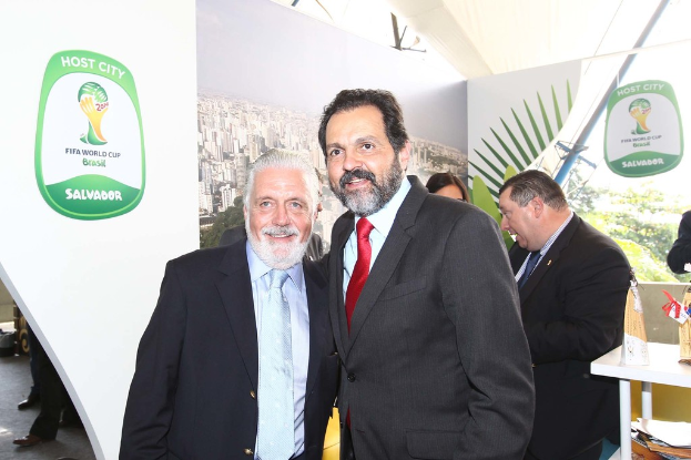 Eine Gruppe von Menschen, die mit einigen, die lächeln, und einem FIFA-Weltmeisterschaftsposter im Hintergrund stehen.