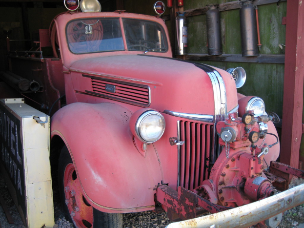 Ein Kraftfahrzeug steht auf einem steinbedeckten Boden, mit Feueröschern an der Wand daneben.