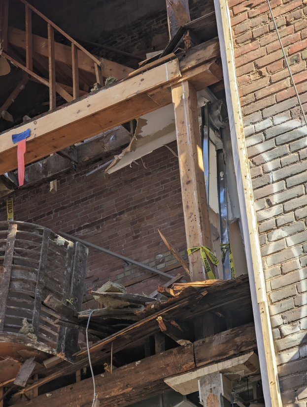 Ein teilweise demoliertes Gebäude mit verstreuten Holzplanken und Trömmern sowie zerbrochene Fenster und Türen.