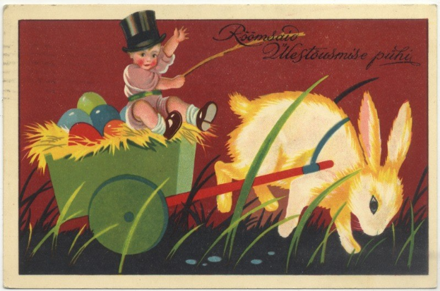 Ein altes Postkartensuvenir mit einem Baby in einem Zylinder, das einen Karren voller bunter Ostereier schiebt, begleitet von einem Hasen und handgeschriebenen Ostergrüßen.