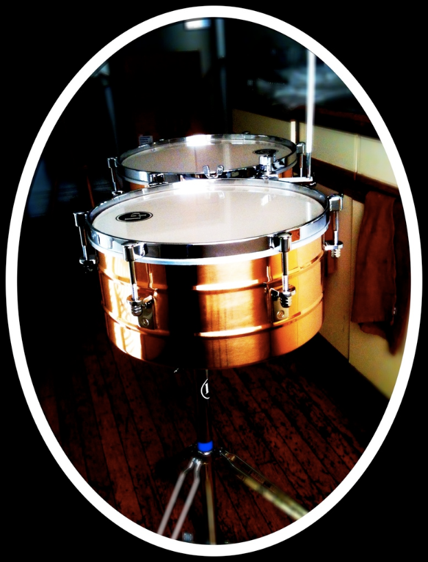 Eine Sammlung von Musikinstrumenten, darunter eine Gitarre, ein Saxofon und ein Schlagzeug, angeordnet auf einem h├Âlzernen Boden.