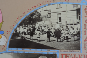 Schwarz-weiß-Foto von Kindern, die in einer Straße mit Gebäuden, Bäumen und einem Zaun im Hintergrund spielen.