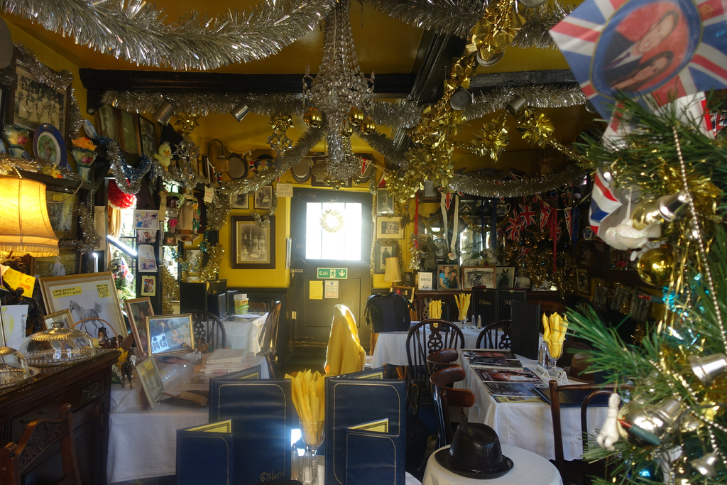 Ein Raum mit Stühlen, Tischen, dekorativen Gegenständen und Fotos an der Wand.