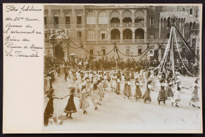 Ein Schwarz-Weiß-Foto von Menschen in traditioneller Kleidung, die vor einem Gebäude mit Fenstern, Bögen, Säulen und Geländern tanzen, mit einem Pfahl mit Gegenständen darauf rechts und Text links, das eine Karnevalsveranstaltung in Paris vermuten lässt.