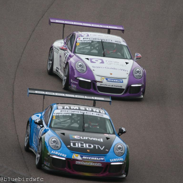 Zwei Autos auf einer Straße außerhalb der Stadt, mit Text in der linken unteren Ecke.