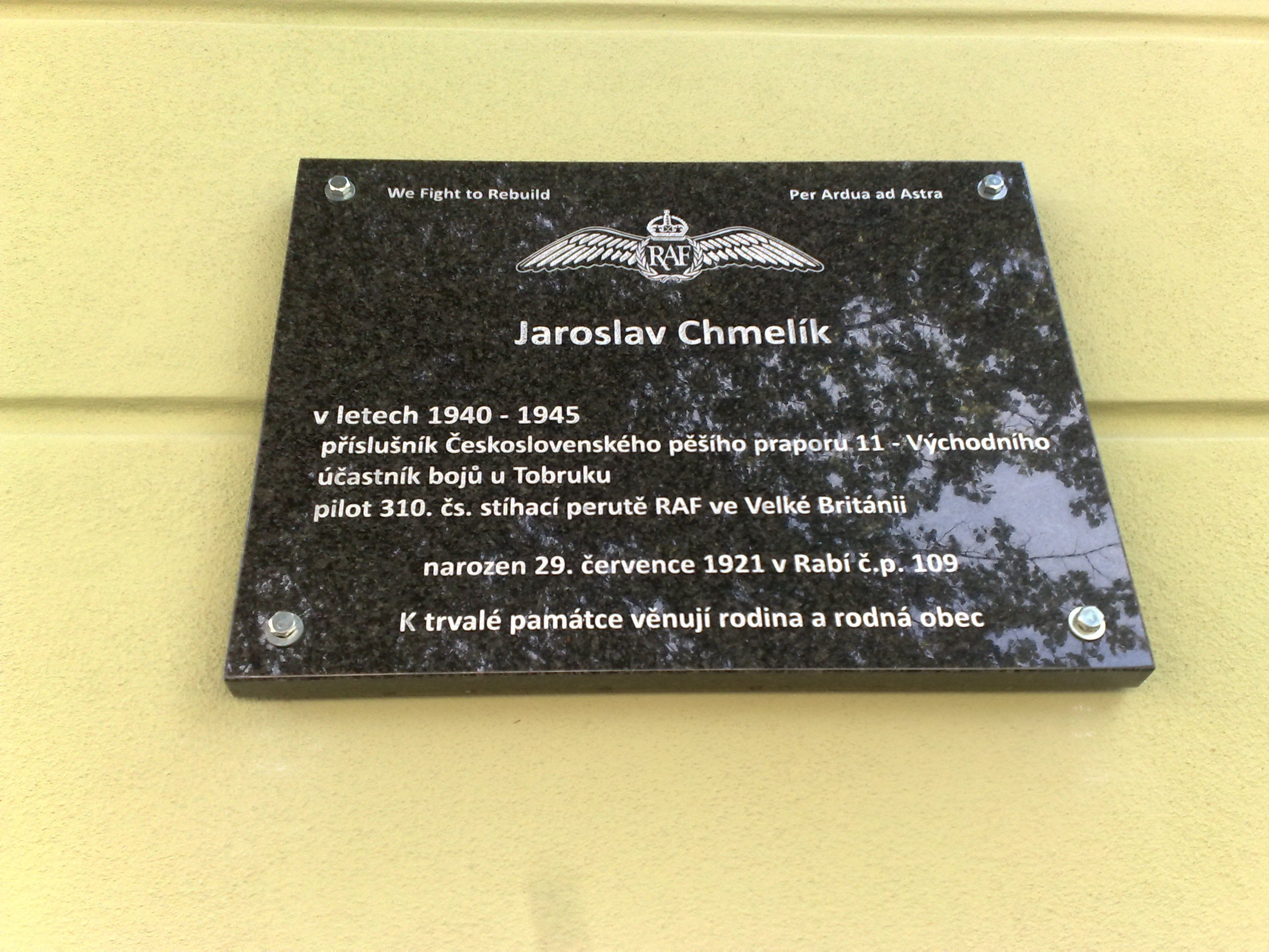 Schwarze Plakette mit weißer Beschriftung, die 'Jaroslav Chmelik' auf einem Gebäude anzeigt, mit einem dekorativen Rahmen.