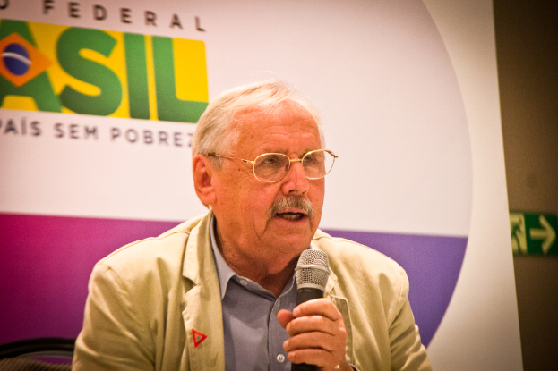 Eine Person, die in ein Mikrofon spricht und von einem Banner mit der Aufschrift "Bundes" hinter ihr flankiert wird.