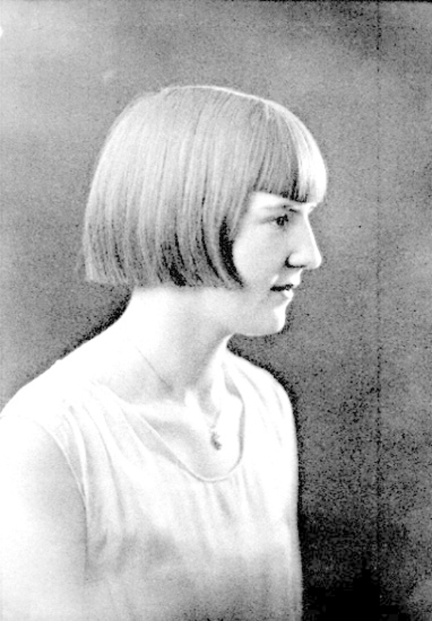 Ein Schwarz-Weiß-Foto einer Frau mit einem kurzen Bob-Haarschnitt, ihr Gesicht ist deutlich zu sehen, die Augen schauen zur Seite und die Lippen sind leicht geöffnet.