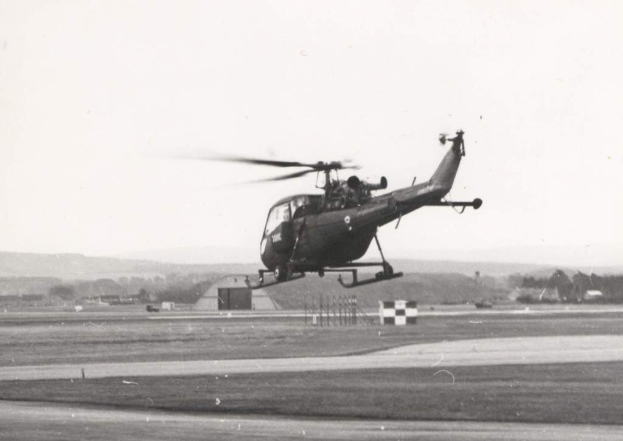 Ein Helikopter in der Luft mit sichtbaren Eisenstangen darunter.