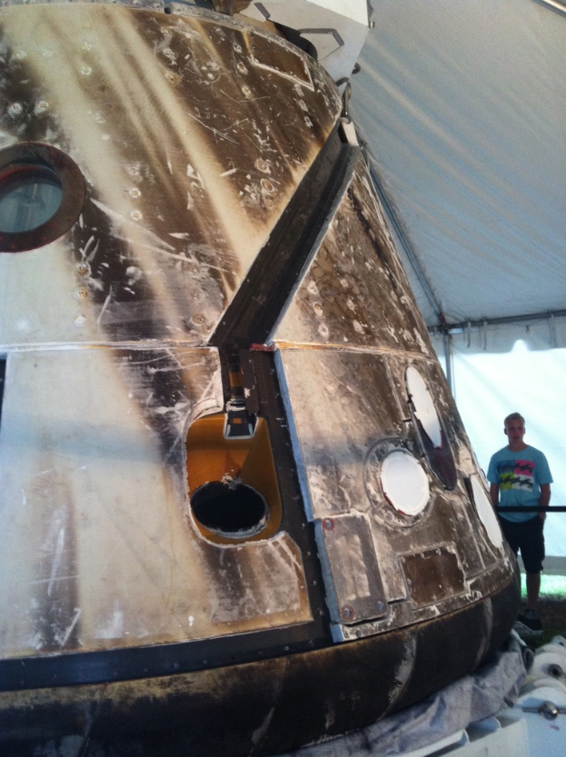 Eine Person steht unter einem Zelt vor einem Objekt.