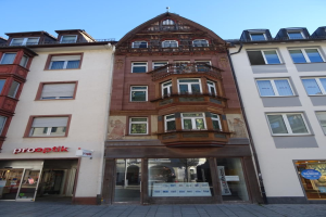 Gewerbliches Gebäude mit mehreren Fenstern, das an einer Straße unter einem klaren blauen Himmel zum Verkauf steht in Heidelberg, Deutschland.