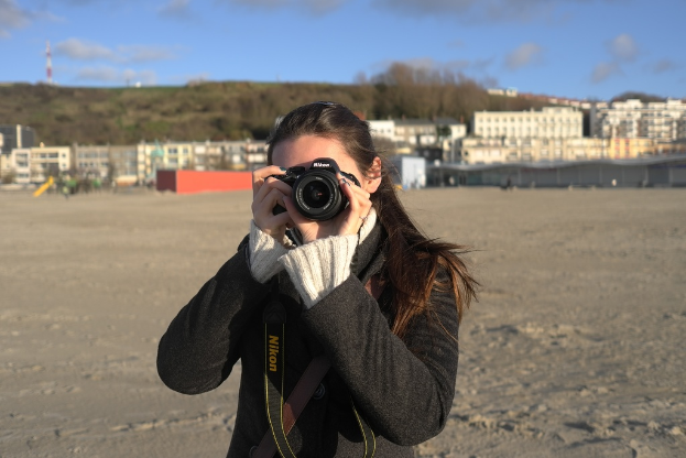 Eine Frau mit einer Kamera vor einem Gebäude.