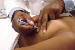 Ein Arzt in einem weißen Laborkittel setzt einem Patienten eine Spritze.