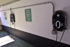 Ladestationen für Elektrofahrzeuge an einer Wand in einer Tiefgarage, mit Informationsschildern darunter.