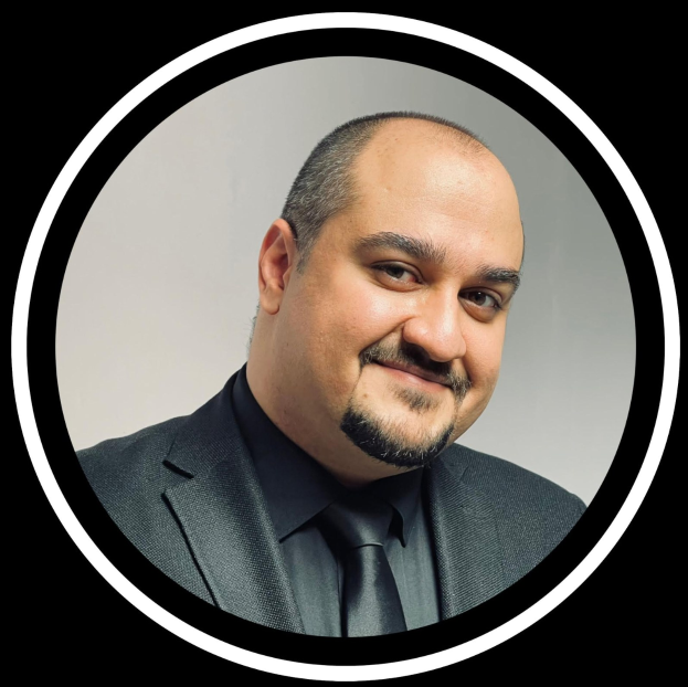 Ein Mann in Anzug und Krawatte mit einem Lächeln vor einem schwarzen Hintergrund, als Anwalt in New York City bezeichnet.