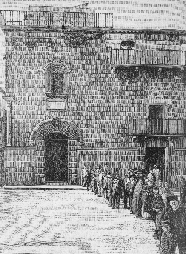 Schwarzes und weißes Foto einer Gruppe von Menschen, die vor einem Gebäude mit Fenstern, Geländern und einer Tür stehen, mit Text unten, der lautet: "Jüdische Gefangene am Eingang zur Synagoge in Jerusalem."