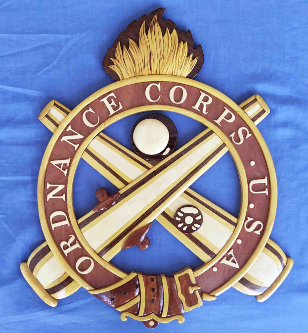 Holzschild mit "Ordnance Corps"-Text, das eine geschnitzte weiße Stern auf einem navyblauen Hintergrund mit einer goldenen Umrandung zeigt, auf blauem Tuch montiert.