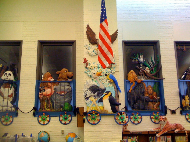 Ein Gebäude mit einer Wand, an der eine Flagge hängt, umgeben von verschiedenen Gegenständen wie Spielzeugen, Büchern und Globus.