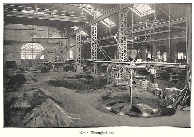 Schwarzes und weißes Foto eines Fabrikinneren mit Arbeitern, die an Maschinen arbeiten, Metallstangen und -rohre sowie die Beschriftung "Neue Eisenglebeerei, die erste Fabrik in Deutschland" am unteren Rand.