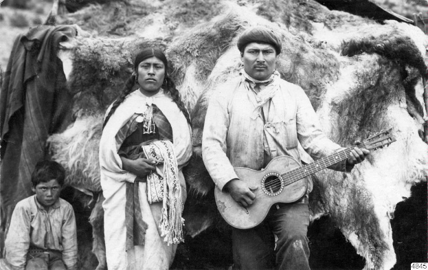 Schwarzes und weißes Foto eines Mannes, der eine Gitarre hält, neben einer Frau und einem Kind.