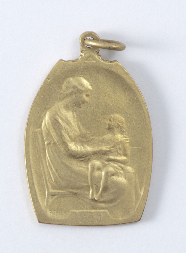 Goldmedaille mit einer Reliefdarstellung einer Frau in einem weißen Kleid mit einem Dutt, die ein Kind hält, beide schauen sich zärtlich an, beschriftet mit "Mutter und Kind."