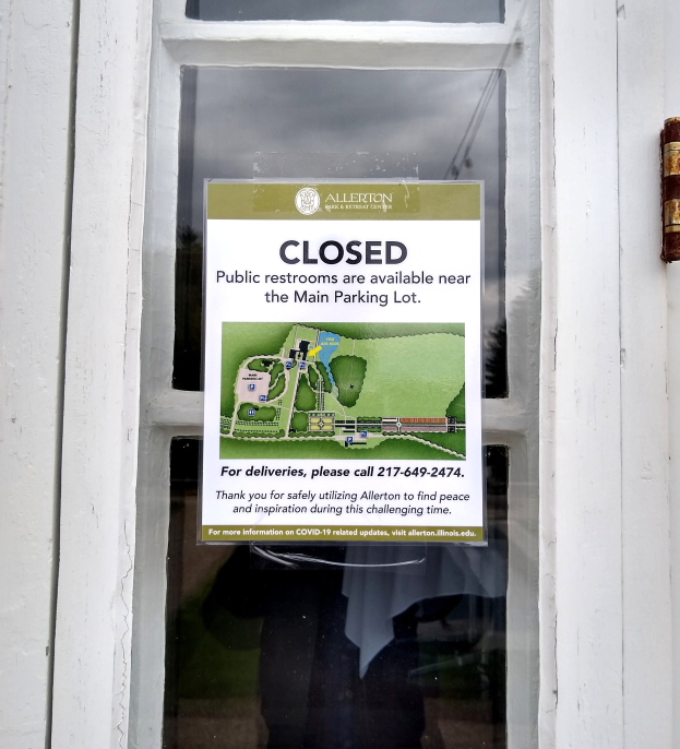 Glasstür mit einem Schild, auf dem "Geschlossene öffentliche Toiletten in der Nähe des Hauptparkplatzes" steht und ein unklares Objekt auf der rechten Seite.