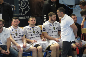 Eine Gruppe von Männern sitzt auf einer Bank, einige halten Flaschen, im Hintergrund eine Fahne mit der Aufschrift "Nordkraque vs Bordeaux."