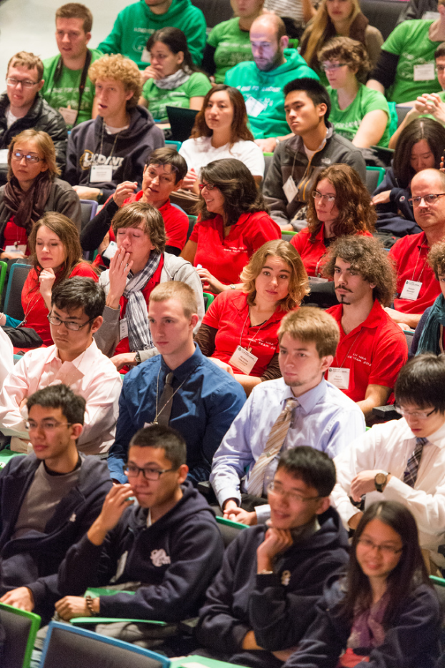 Eine Gruppe von Menschen, die drinnen sitzen, einige mit Laptops und andere mit Akten.