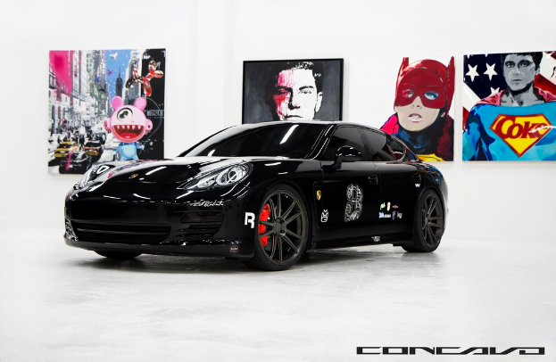 Ein schwarzer Nissan-Sportwagen parkt vor Cartoon-Postern, mit einer kleinen Inschrift am unteren Rand des Bildes.