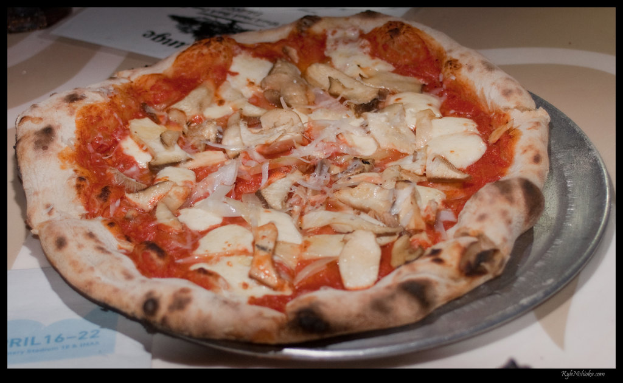 Eine Pizza mit verschiedenen Belägen auf einem Teller, der auf einem Tisch steht.