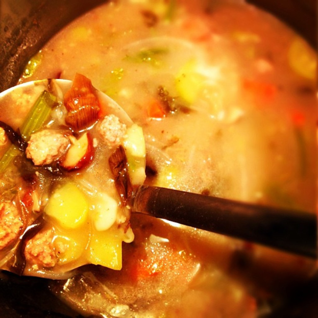 Ein Nahaufnahme eines Currys in einem Gefäß mit einem schwarzen Löffel davor.