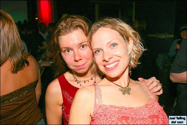 Eine Gruppe von Menschen mit zwei lÃ¤chelnden Frauen in der Mitte und einem Licht im Hintergrund.