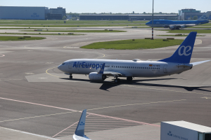 Air Europa Airbus A320-200 auf der Rollbahn am Frankfurter Flughafen, umgeben von Gras, Pfählen, Gebäuden, Bäumen und einem klaren blauen Himmel.