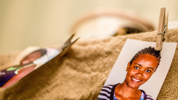 Auf einem Tisch befinden sich ein Papierclip, ein passportgroßes Foto und ein Stoffstück auf der rechten Seite, während Hintergrund und linke Seite unscharf sind.