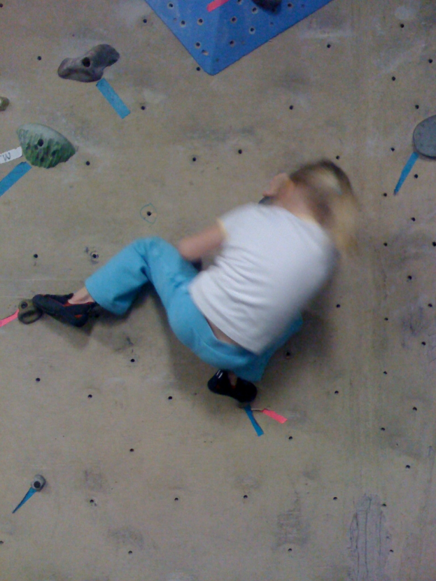 Ein Kind klettert an einer Boulderwand.