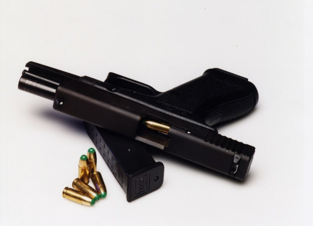 Eine schwarze Pistole mit einem Magazin und Patronen auf einer weißen Oberfläche.