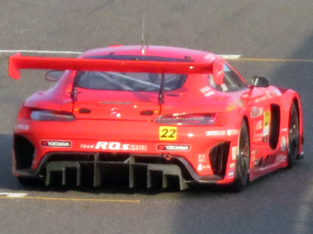 Roter Porsche 911 GTS Rennauto auf einer Rennstrecke mit aerodynamischem Design, großem Heckspoiler, breiter stance und schwarzen Rädern.