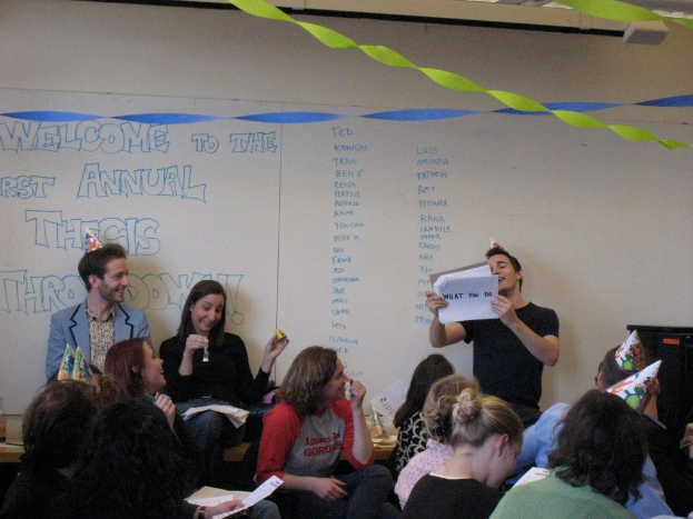 Eine Gruppe von Menschen feiert ihren ersten jährlichen Thesistreff, mit Bändern auf dem Dach und einigen Personen mit Mützen.