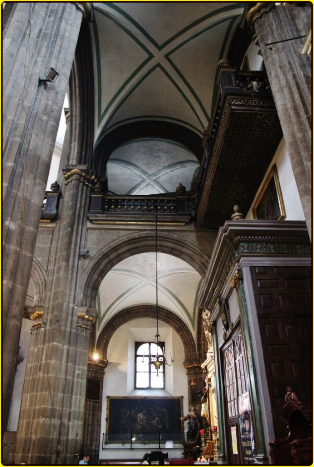 Ein Innenblick auf einen Palast mit Schränken, beleuchteten Säulen, Wandskulpturen, einem großen Rahmenbild und einer Deckenleuchte.